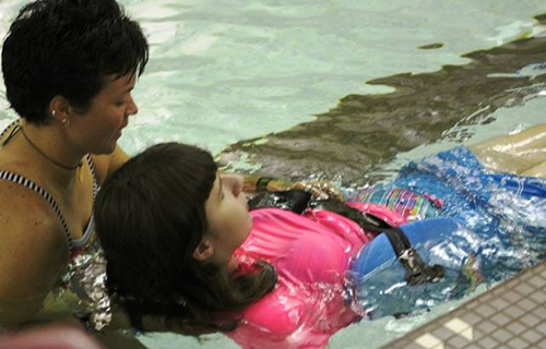 Woman assisting a girl in the pool