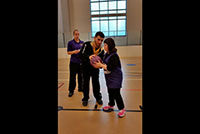Student teaching a child to play basketball