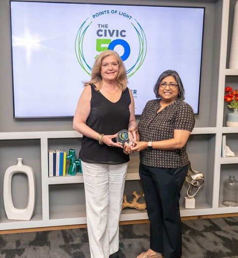 Helen Hammerschmidt and Rita Patel-Eng receive Civic50 award standing in front of Civic50 banner