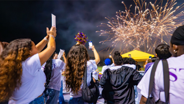 Students take photos of fireworks at Farrell Stadium during Rams Under the Lights