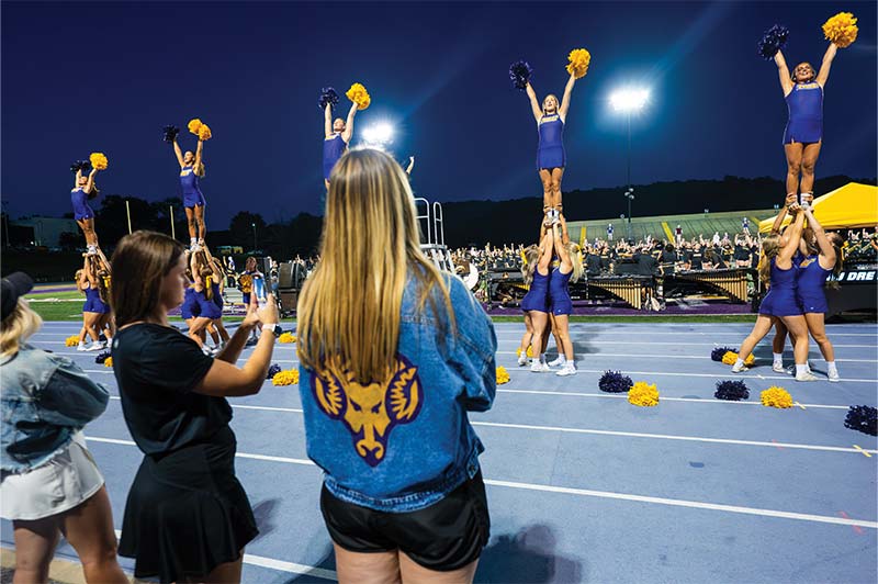 Students watch and take pictures as the WCU cheerleaders are in formation doing their routine