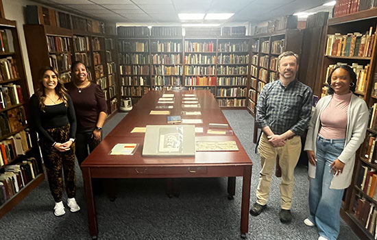 Group of 4 people in library infront of frederick douglass information