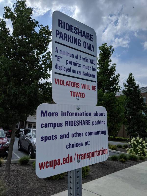 Two rideshare parking spots with a white car parked in front